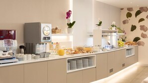 Una barra de desayuno moderna con una máquina de café, dispensador de zumo y diversas opciones para el desayuno.