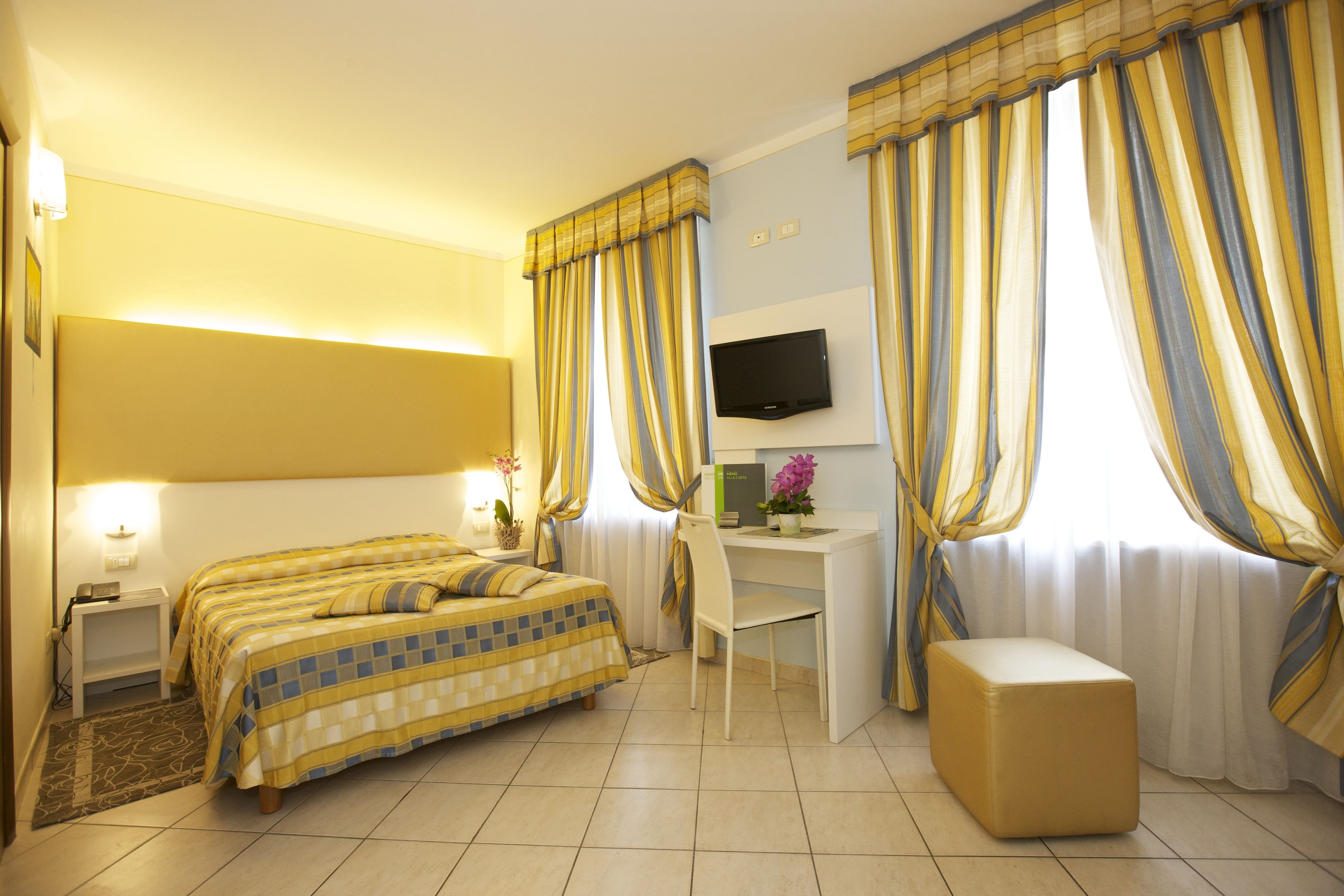 Una habitación de hotel con cama, escritorio, silla y televisión.