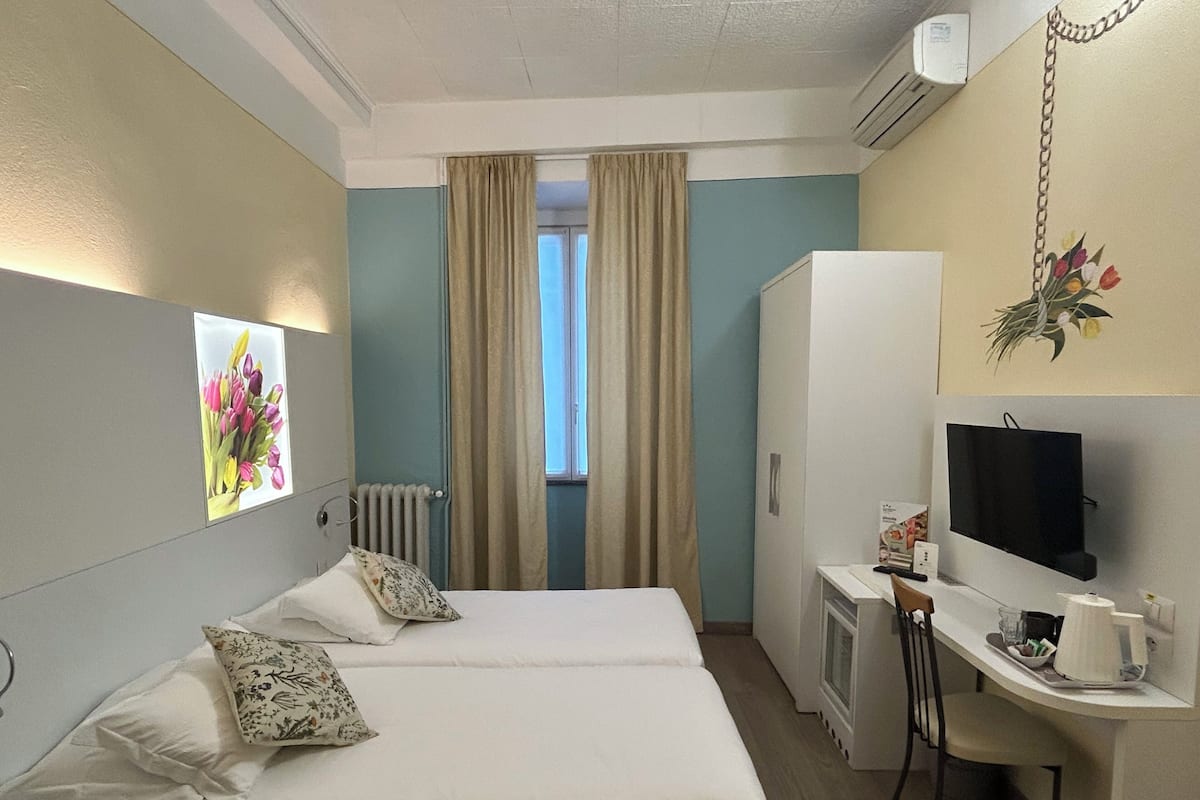Habitación de hotel con dos camas, un escritorio, un televisor y un radiador.
