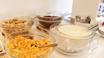 Ein reichhaltiges Buffet mit verschiedenen Speisen, darunter Müsli, Schokolade und Joghurt.