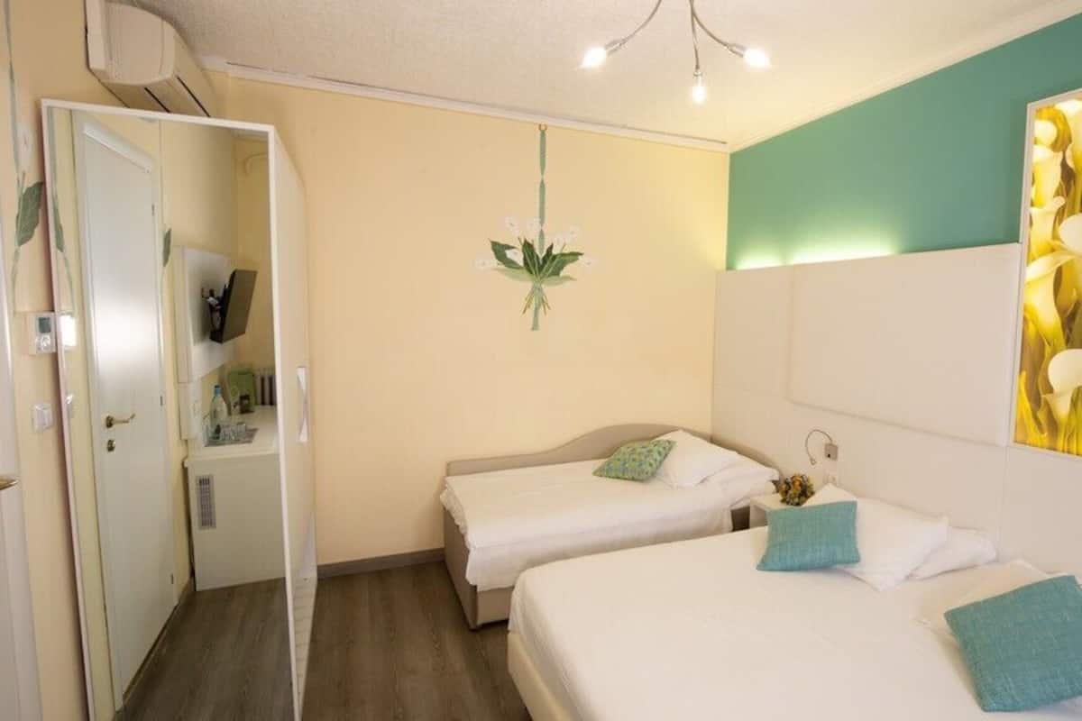 Habitación de hotel con dos camas, un espejo, una obra de arte colgada en la pared y una puerta que da al baño.