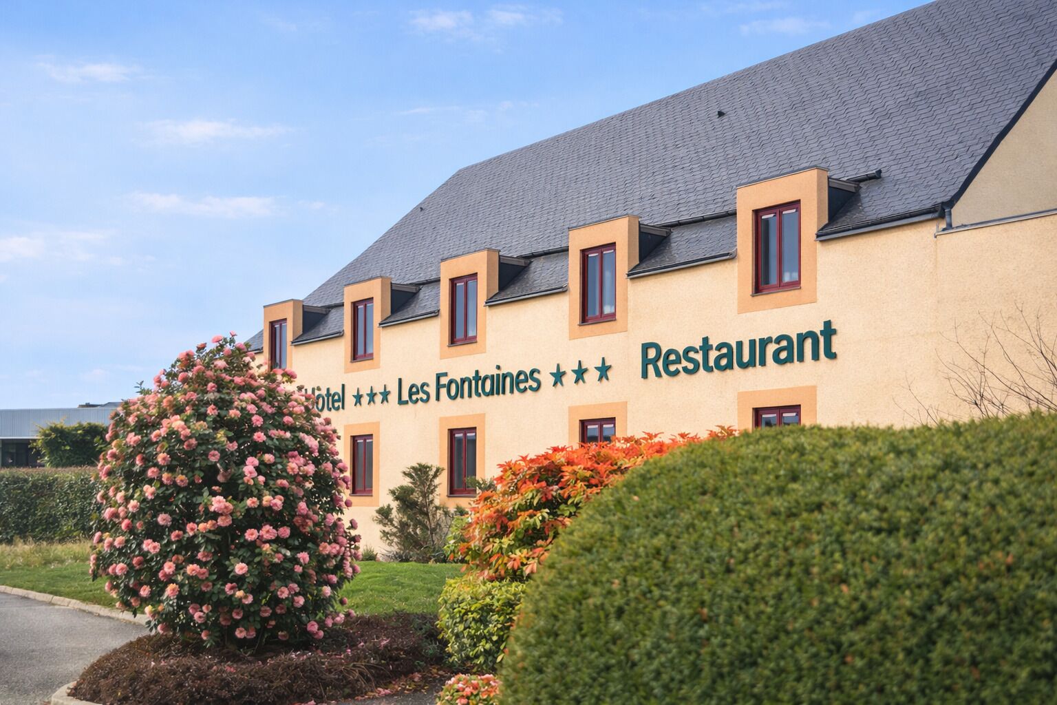 Un edificio di un hotel con un cartello che recita 'Hotel *** Les Fontaines Restaurant'.
