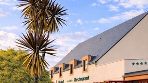Un hotel con restaurante, una palmera y cielo despejado.