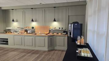 Une cuisine moderne dotée d’un îlot central, de luminaires suspendus et d’un réfrigérateur.