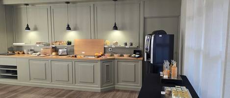 A modern kitchen with a central island, pendant lighting, and a refrigerator.