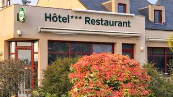 A hotel with a sign reading 'Hôtel Restaurant' and a satellite dish on the roof.
