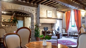 Un intérieur rustique avec des murs en pierre, des poutres en bois, une cheminée et des sièges confortables.