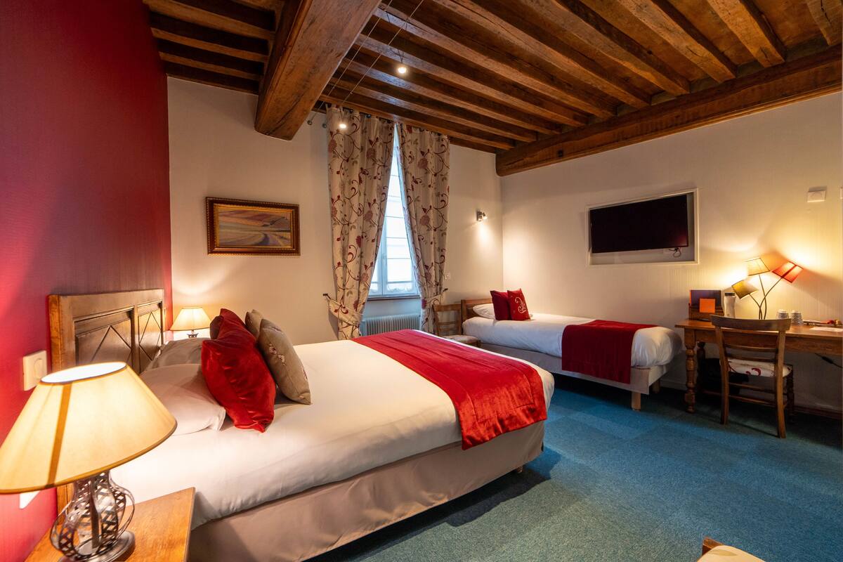Habitación de hotel con dos camas, un escritorio, una silla, un televisor y una ventana con cortinas.