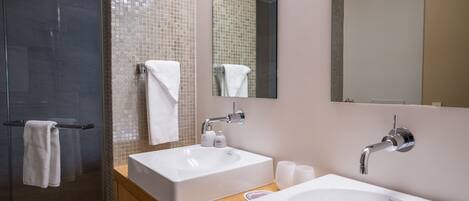 Une salle de bain moderne avec une douche à parois de verre, un grand miroir, deux vasques et un meuble-lavabo en bois.