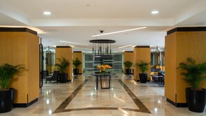 Een moderne lobby met een ronde centrale tafel, potplanten en zithoeken.