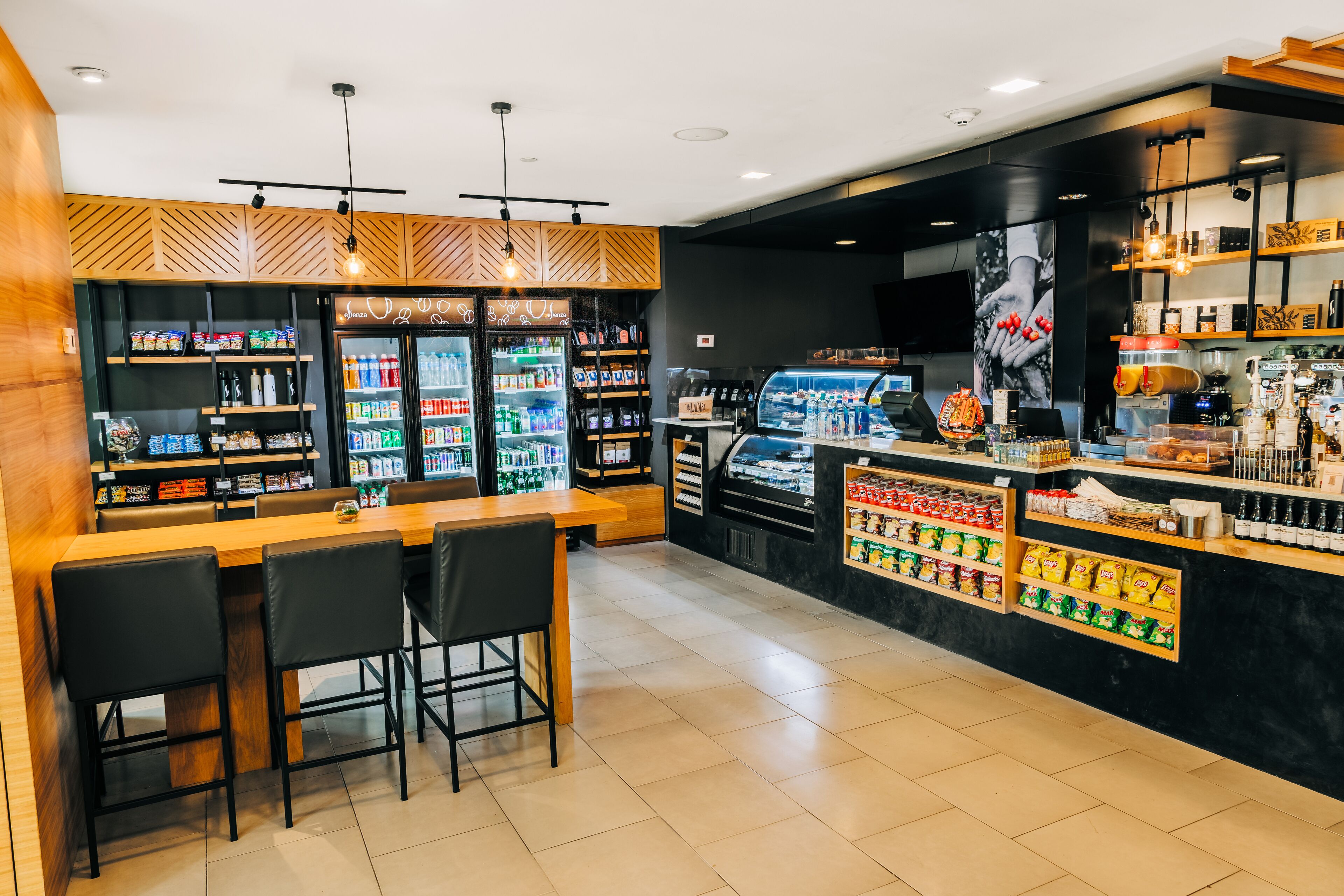 A modern cafe with a bar area, seating, and a variety of food and drink options.