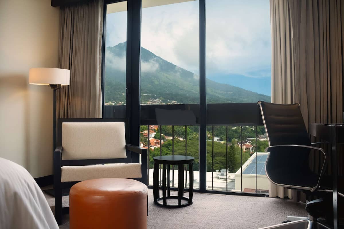 A hotel room with a large window offering a view of a mountain and town.
