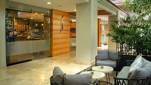 Een moderne hotelentree met een glazen gevel, zithoeken en kamerplanten.