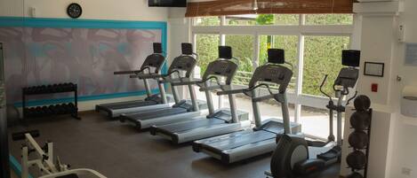 Une salle de sport équipée de tapis de course, d’haltères et d’appareils d’exercice.