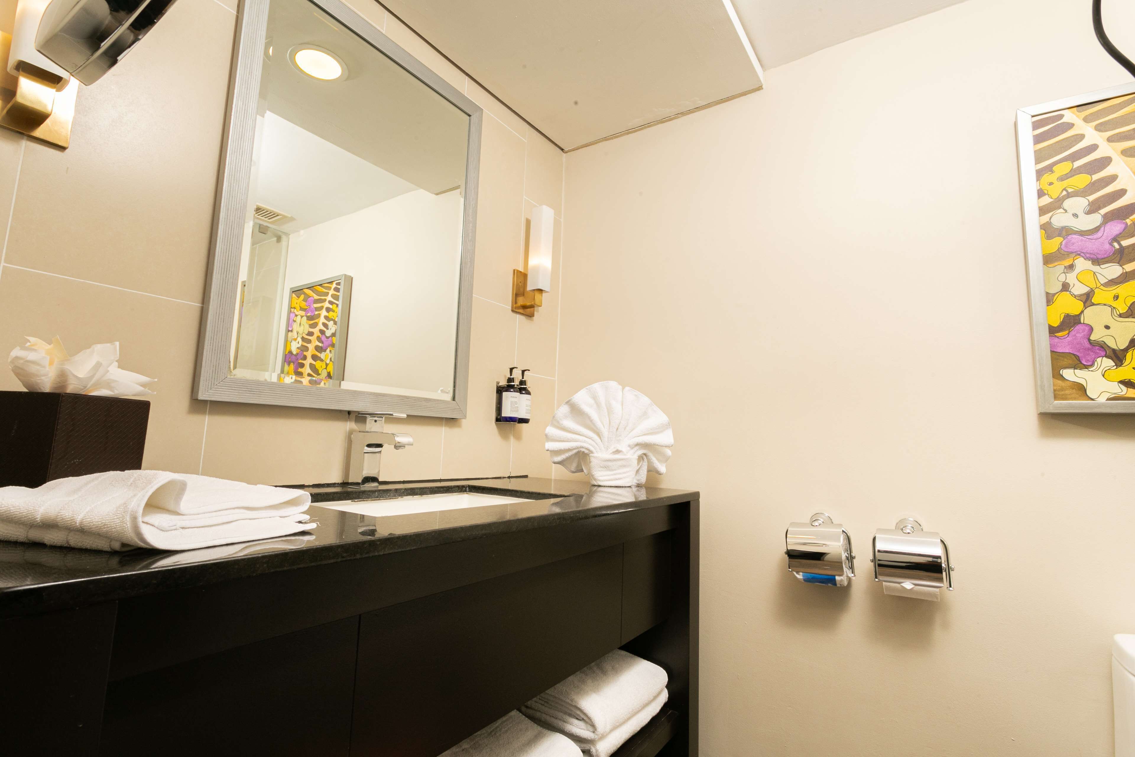 A modern bathroom with a large mirror, a sink, and a towel rack.