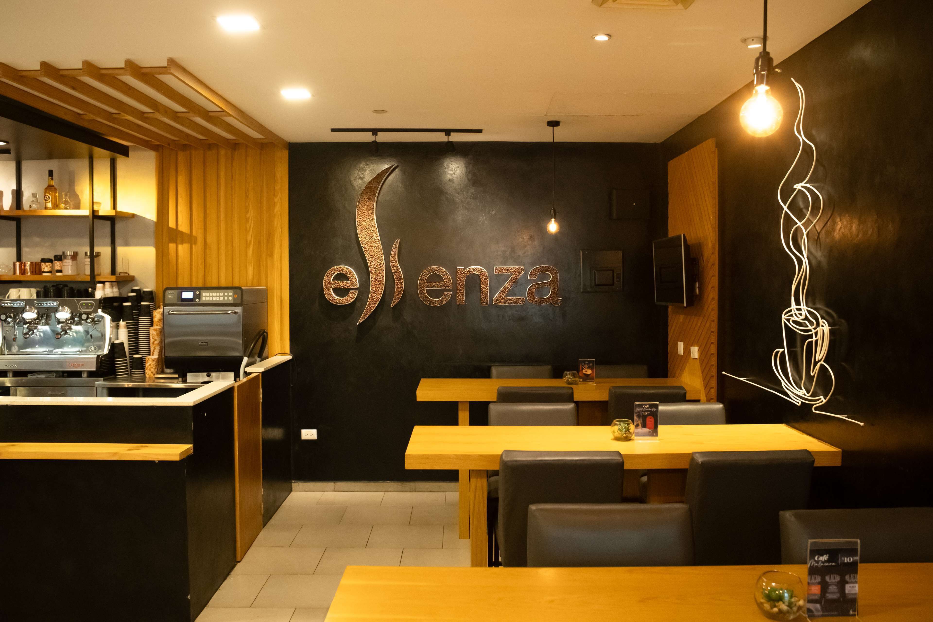 A restaurant interior with a central counter, wooden tables, and black walls.