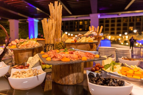 A buffet with various cheeses, meats, and fruits.