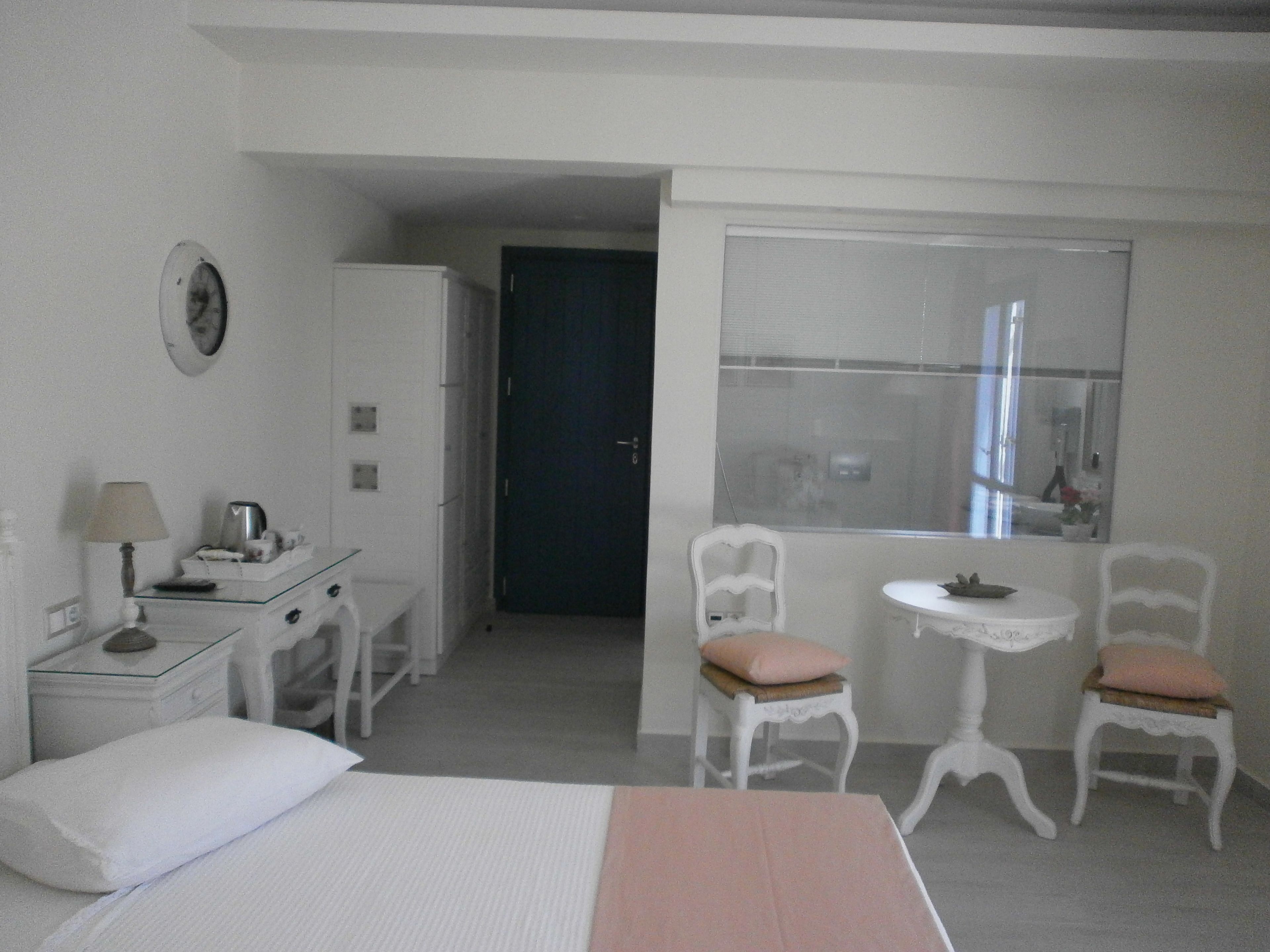 A hotel room with a bed, a desk with a lamp, a chair, a small table, and a window with a view.
