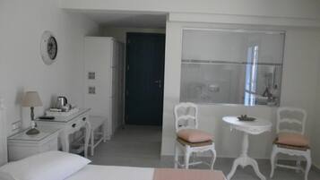 A hotel room with a bed, a desk with a lamp, a chair, a small table, and a window with a view.