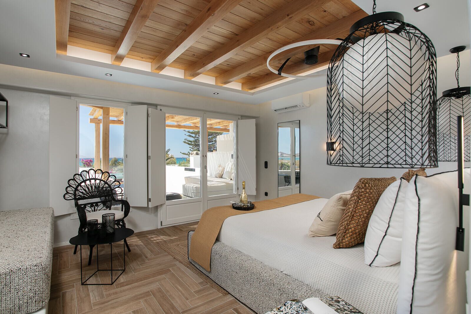 A bedroom with a bed, a chair, a table, and a view of the outdoors.