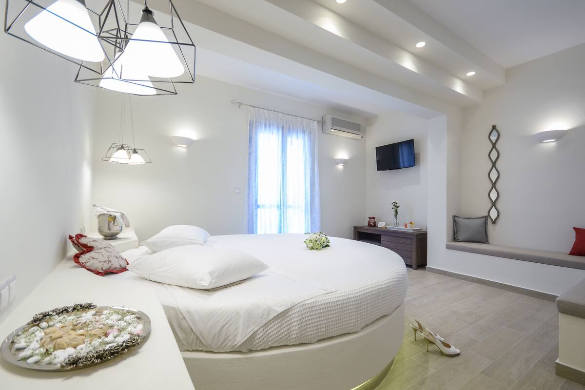 A modern bedroom with a large bed, bedside table, and a TV mounted on the wall.