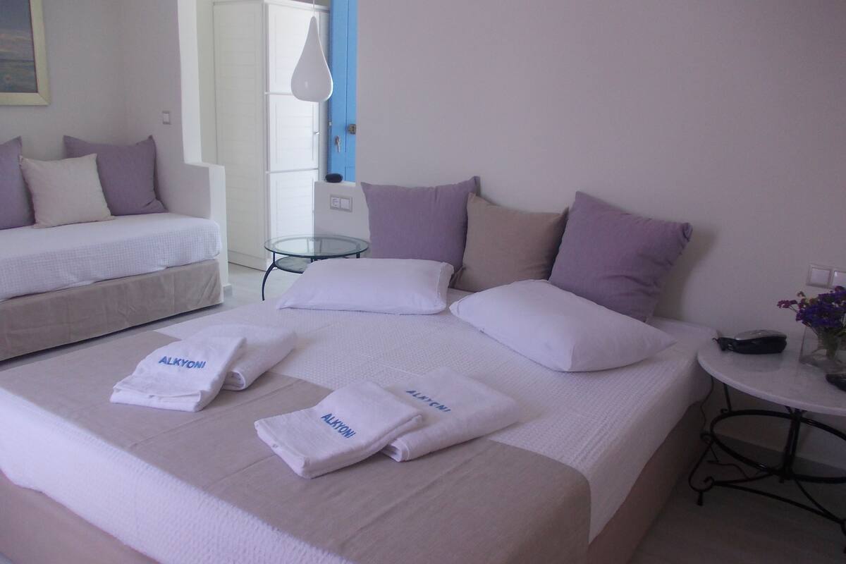 A hotel room with two beds, a small table, and a chair.