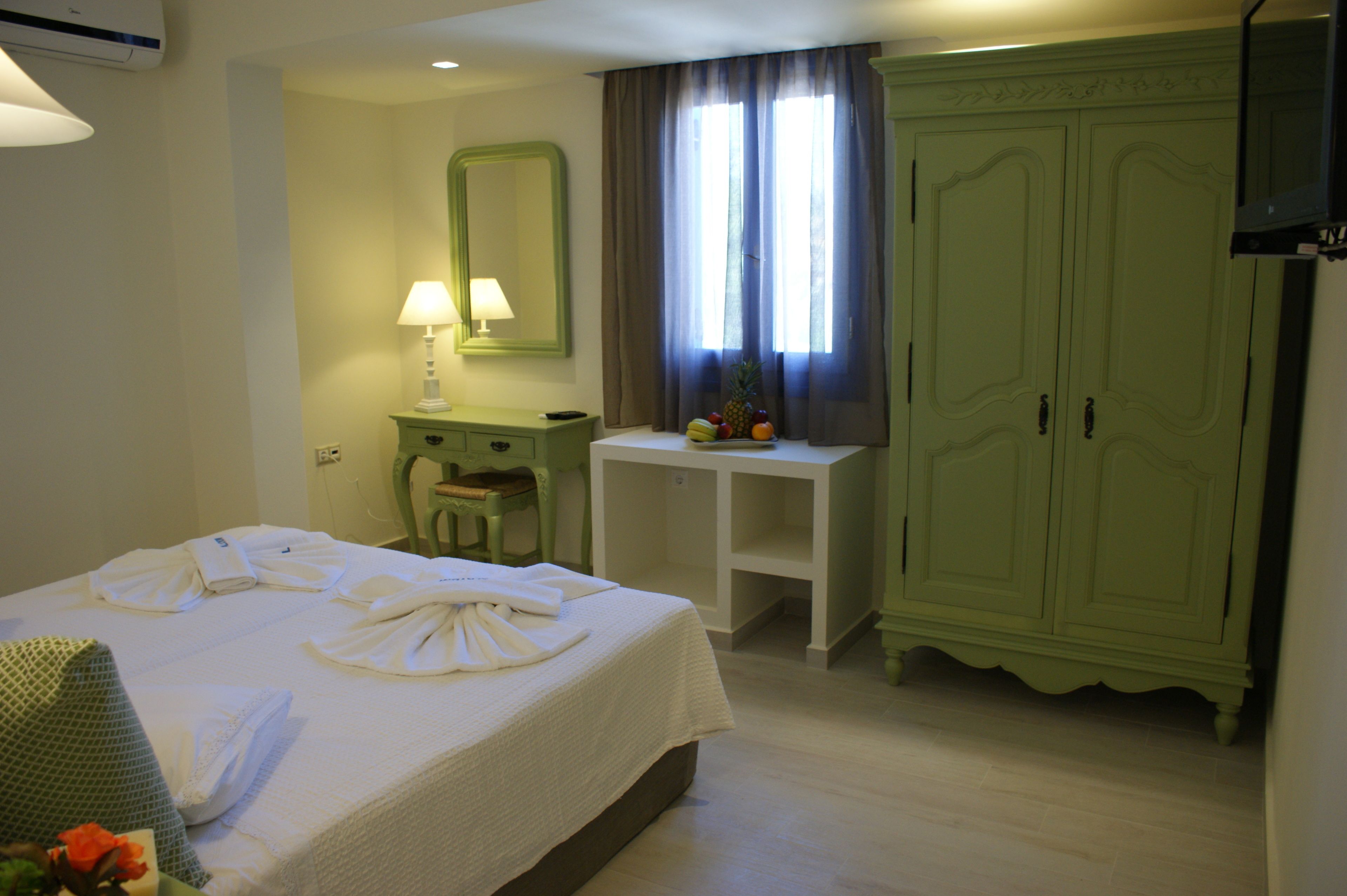 A hotel room with a bed, a desk, a chair, a wardrobe, and a television.
