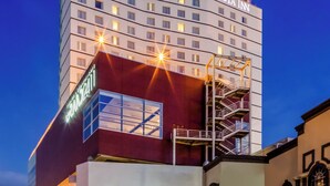 A multi-story hotel with a prominent 'FIESTA INN' sign, a modern architectural design, and a visible staircase leading to the upper floors. - Fiesta Inn Monterrey Tecnológico (Monterrey)