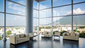 A spacious lobby with large windows offering a view of a cityscape and mountains. - Fiesta Inn Monterrey Tecnológico (Monterrey)