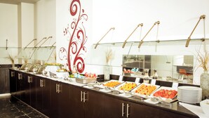 A buffet setup with various food items and a decorative wall with a floral design. - Fiesta Inn Monterrey Tecnológico (Monterrey)