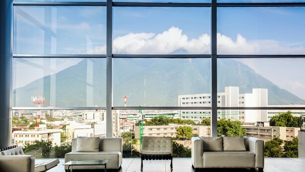 A modern room with a large window offering a cityscape view, including mountains and buildings. - Fiesta Inn Monterrey Tecnológico (Monterrey)