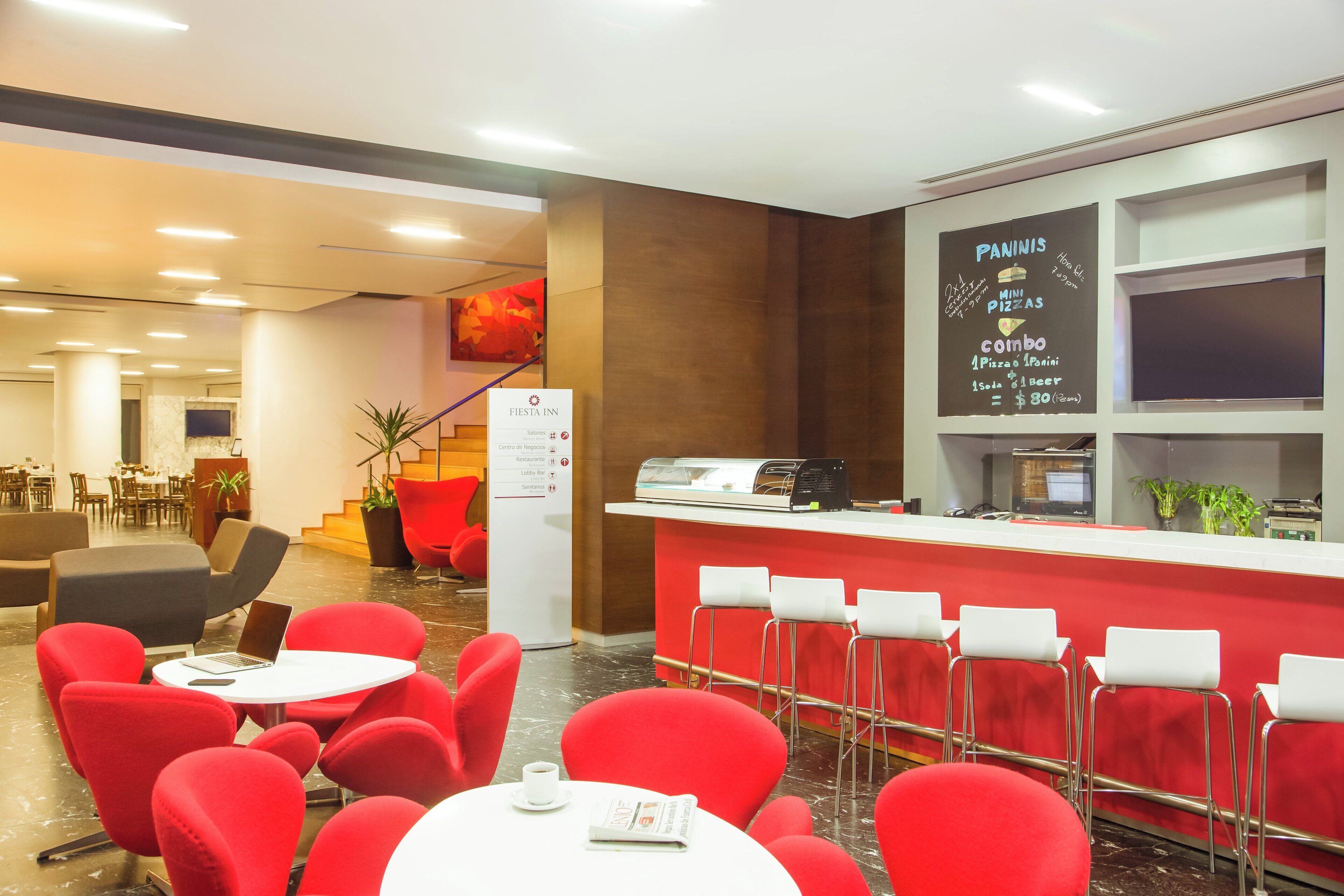 A hotel lobby with red chairs, a reception desk, and a menu board advertising a combo deal.