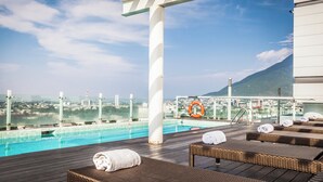 A rooftop pool area with lounge chairs and a view of a city and mountains. - Fiesta Inn Monterrey Tecnológico (Monterrey)