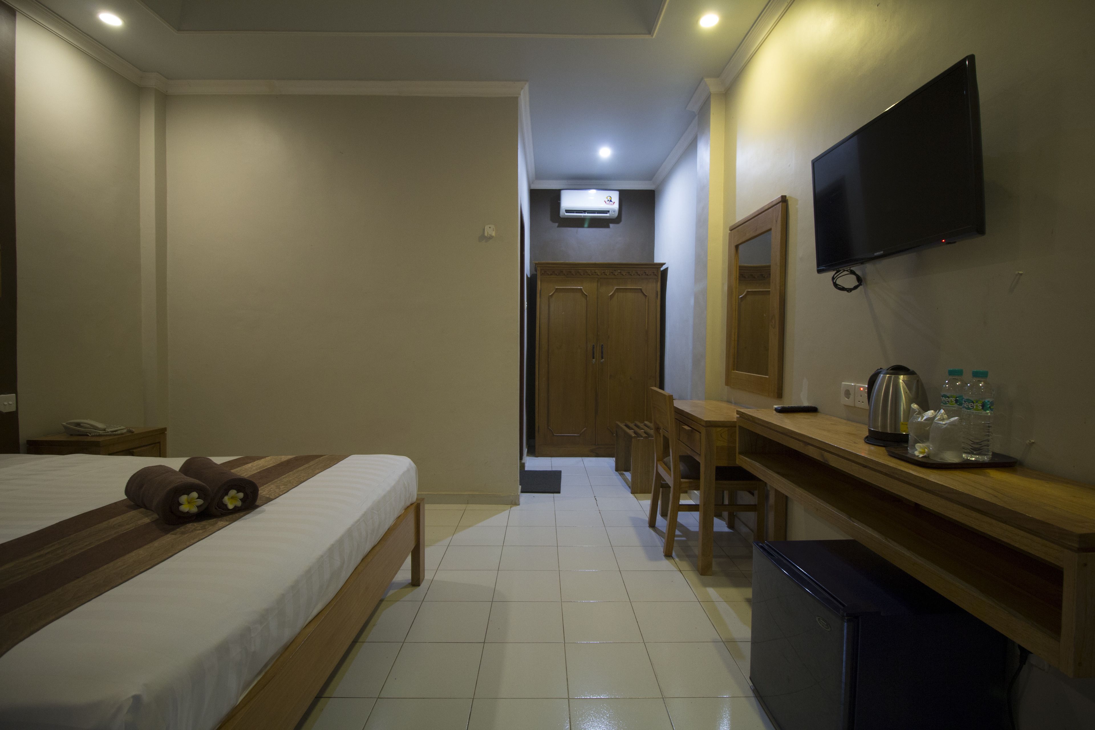 Een hotelkamer met een bed, een bureau, een televisie en een kitchenette.
