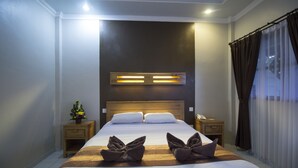 Una habitación de hotel moderna con una cama grande, cabecera de madera, mesitas de noche y un buró con teléfono.