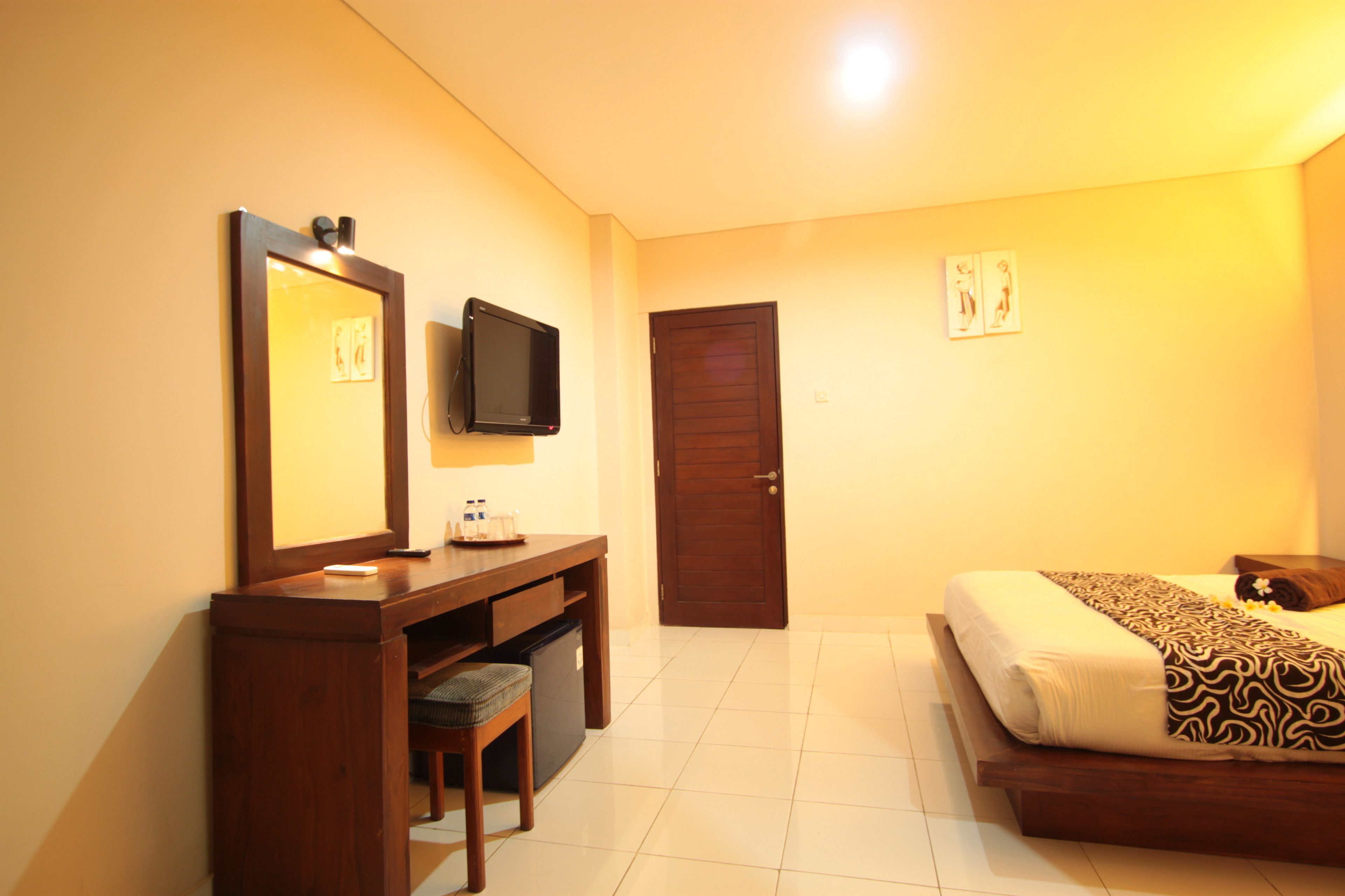 Una habitación de hotel con cama, escritorio con silla, televisor y puerta.