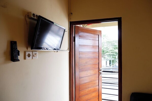A room with a television mounted on the wall, a door, and a window.