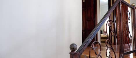 A wooden staircase with ornate metal railings leading to a room with a wooden floor.