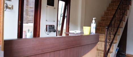A reception area with a wooden counter, a phone, and a bottle of hand sanitizer.