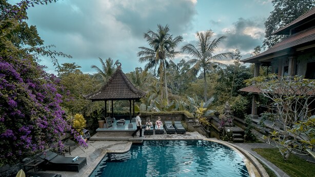 A pool area with lounge chairs, a gazebo, and tropical vegetation. - Nick's Hidden Cottages (Ubud)