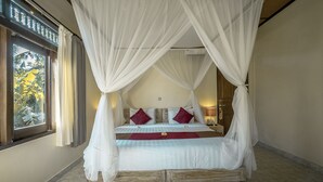 A four-poster bed with white bedding and red pillows, a wooden platform, and a view of tropical foliage through a window. - Nick's Hidden Cottages (Ubud)