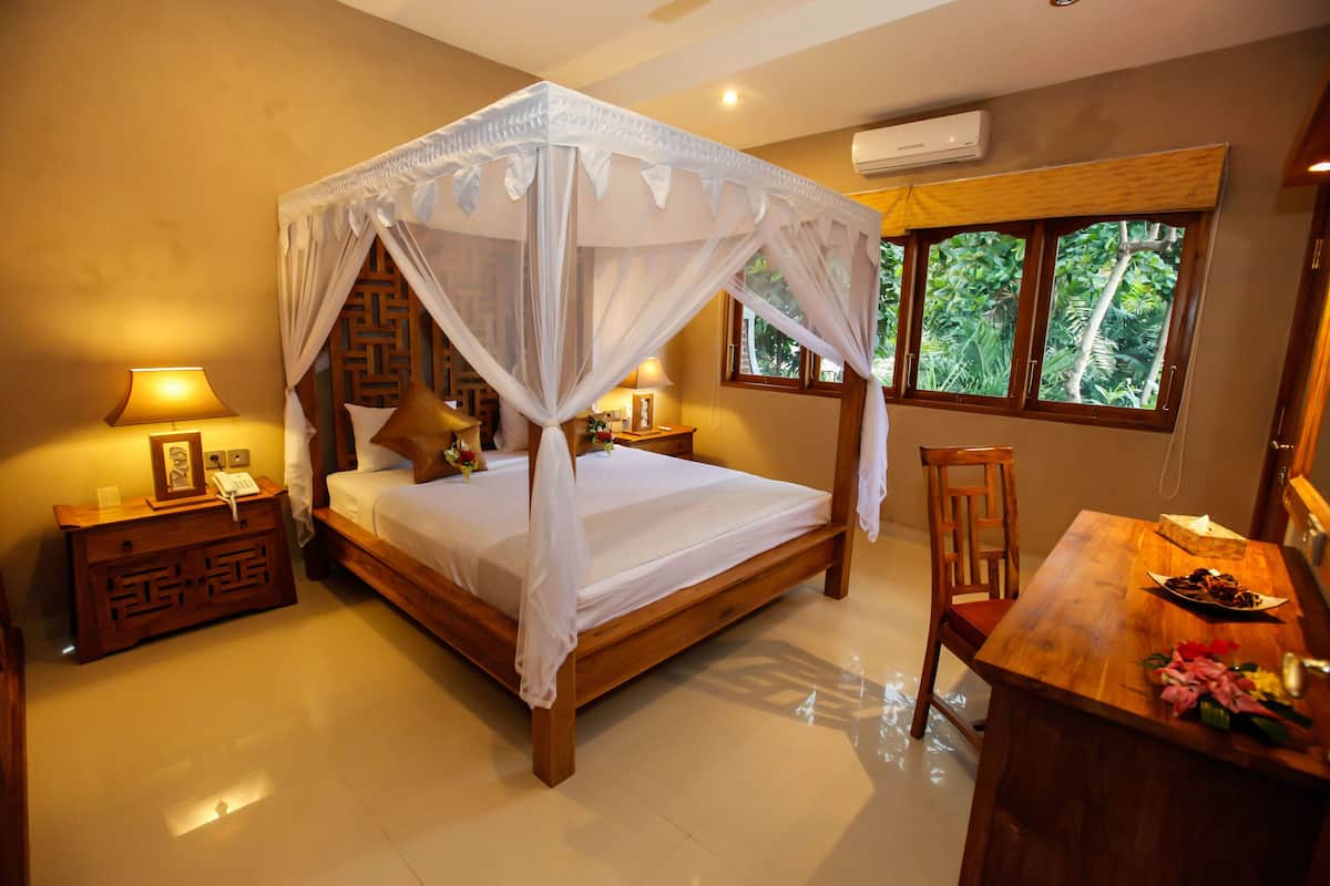 Une chambre à coucher avec un lit à baldaquin, une table de chevet en bois avec une lampe, un bureau en bois sur lequel se trouve une assiette de nourriture, et une fenêtre donnant sur un paysage verdoyant.