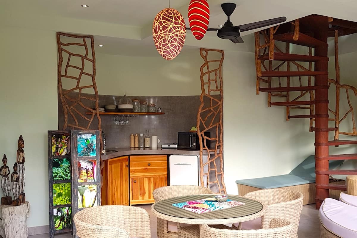 Un espace de vie compact comprenant une cuisine, un coin repas et un lit en mezzanine.