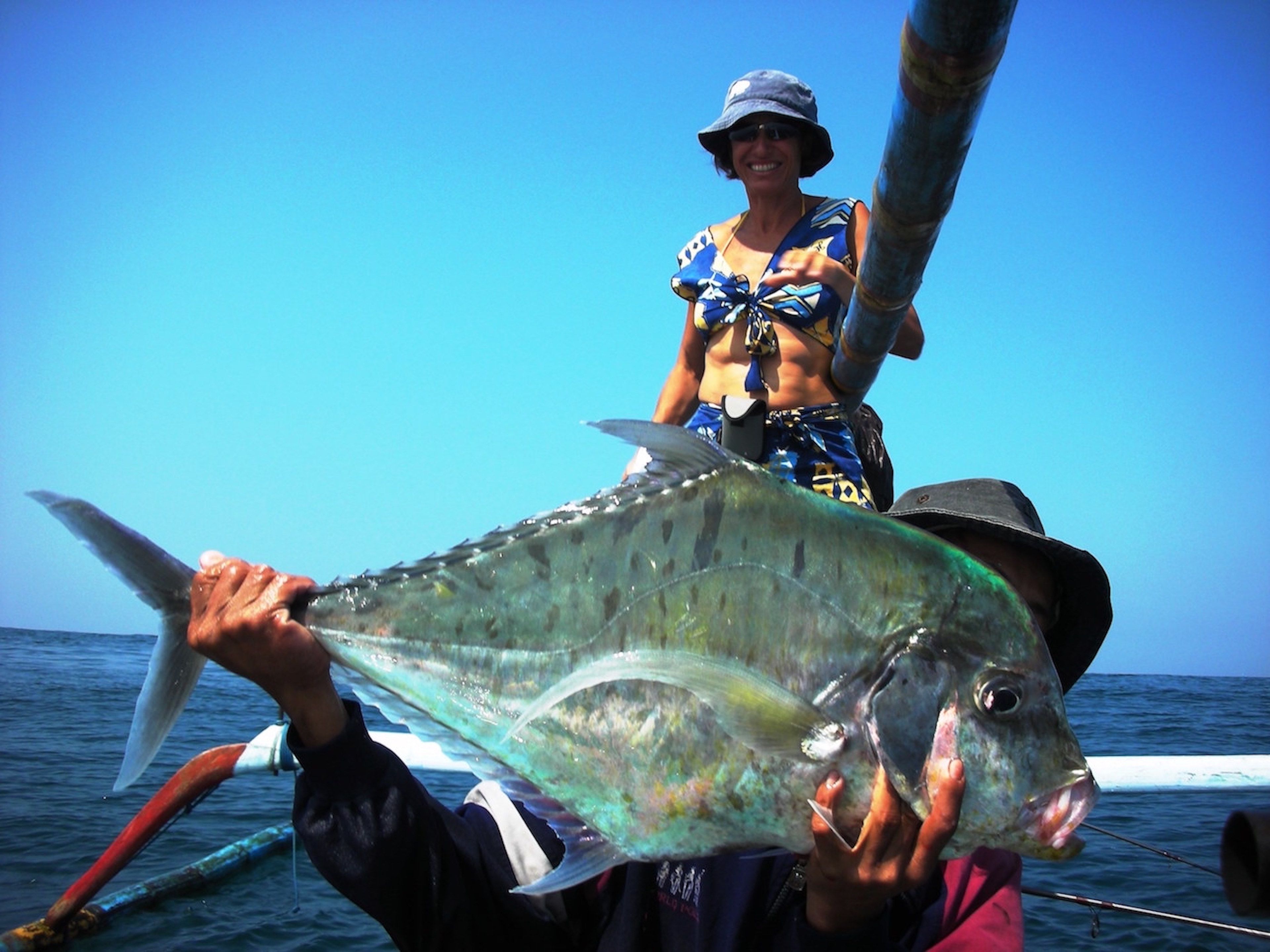 A person holding a large fish on a boat.