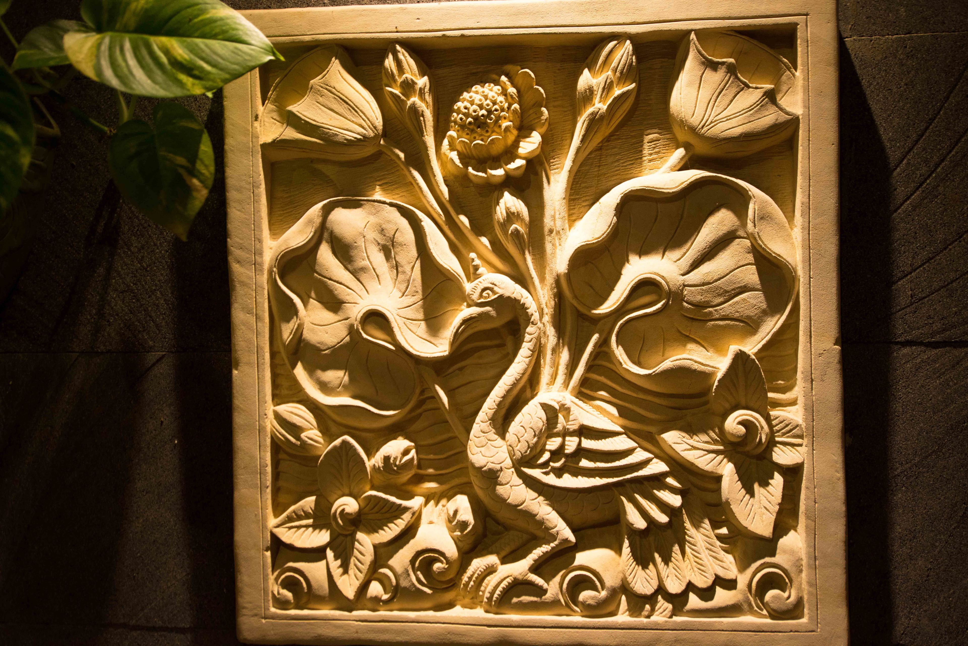 A detailed carved relief of a peacock surrounded by floral elements.