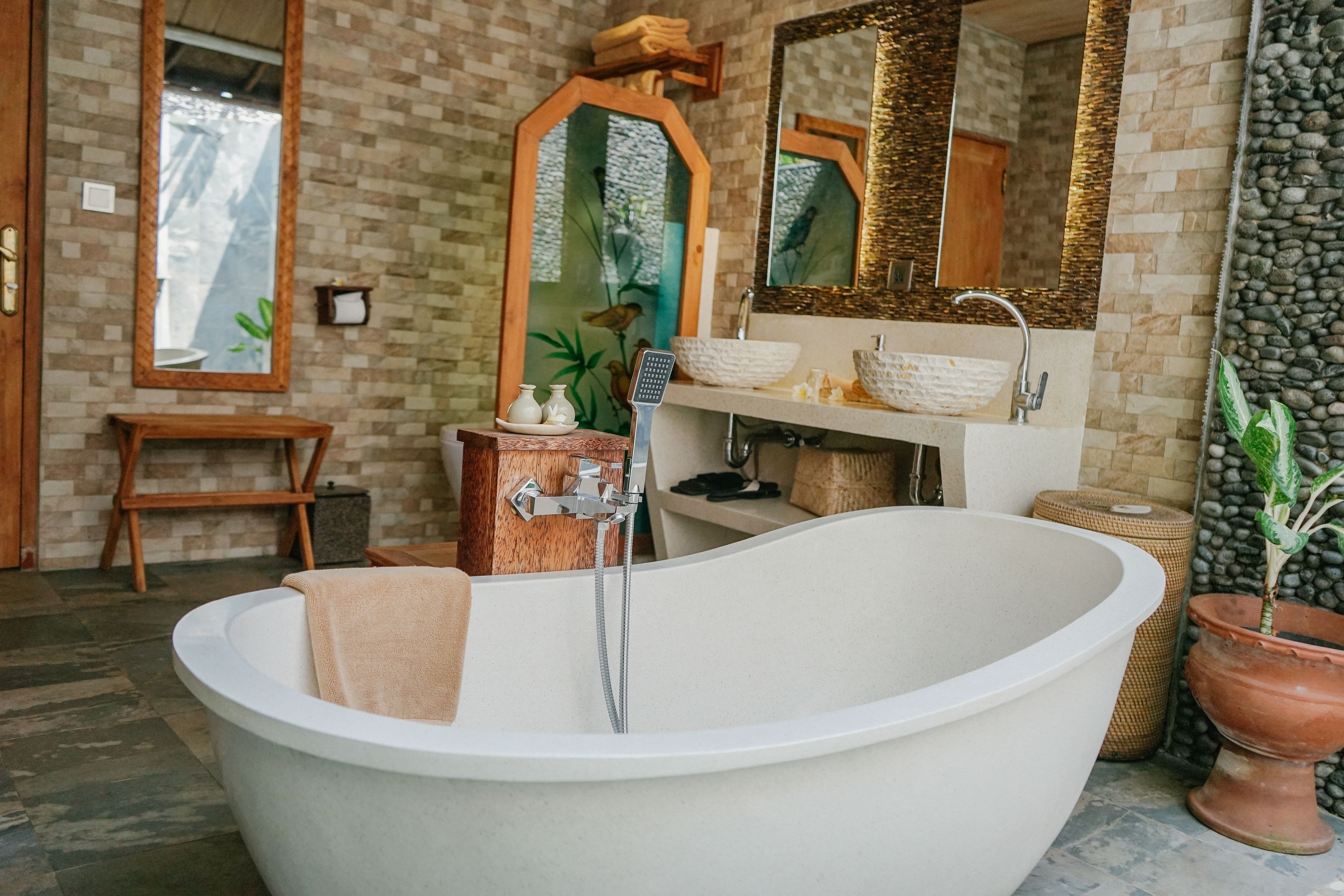 A modern bathroom with a freestanding bathtub, wooden vanity, and a large mirror.