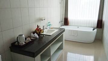Un baño moderno con una bañera grande, un lavabo y una encimera con artículos de aseo.