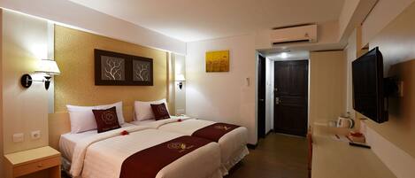 A hotel room with a bed, bedside tables, a TV, and a door leading to a bathroom.