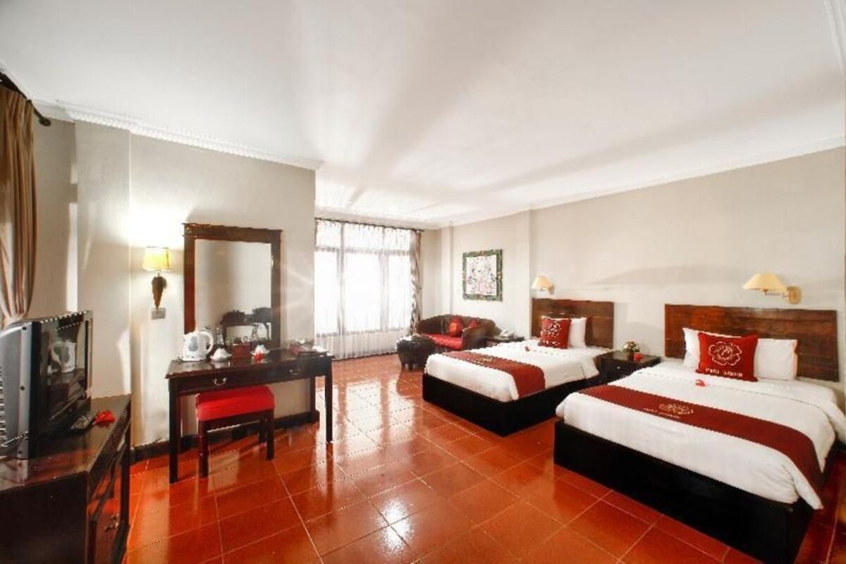 Habitación de hotel con dos camas, un escritorio, una silla, un televisor y una ventana con cortinas.