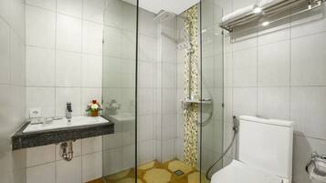 Ein modernes Badezimmer mit einer gläsernen Duschkabine, einer Toilette und einem Waschbecken mit Marmorplatte.